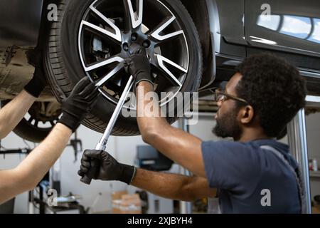 Mechanics working on car wheel in auto repair shop Stock Photo