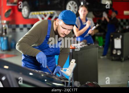 Professional mechanic man in uniform repairing car in auto repair garage Stock Photo