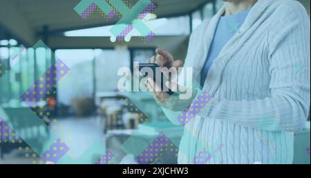 Image of x symbols over midsection of caucasian woman standing and scrolling on smartphone Stock Photo