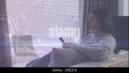 Image of graphs, trading boards, binary codes, biracial woman using smartphone at home. Digital composite, multiple exposure, report, business, stock Stock Photo