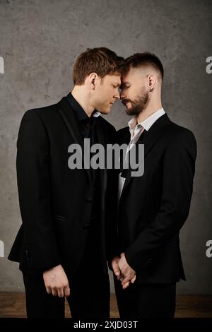 Two men in elegant suits embrace, their foreheads touching in a gesture of affection and intimacy. Stock Photo