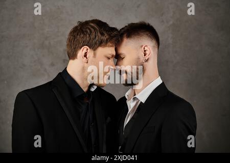 Two men in suits are close together, foreheads touching, in a moment of intimacy. Stock Photo