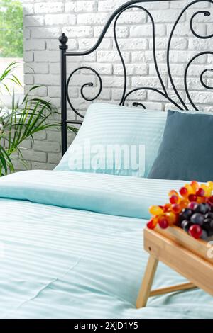 Wooden Breakfast Tray With Teapot, Grapes, and Cup on a Blue Bed Stock Photo