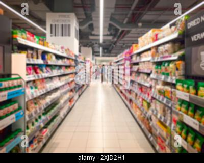 Supermarket aisle with colorful shelves and shoppers. Abstract blur as background. Stock Photo