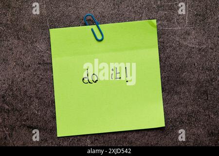 A bright green sticky note with "Do it!" written on it, clipped to a textured background. A powerful visual reminder to take action Stock Photo