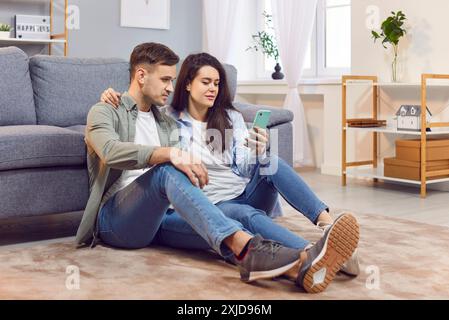 Young Family Using Phone For Online Entertainment At Home Stock Photo