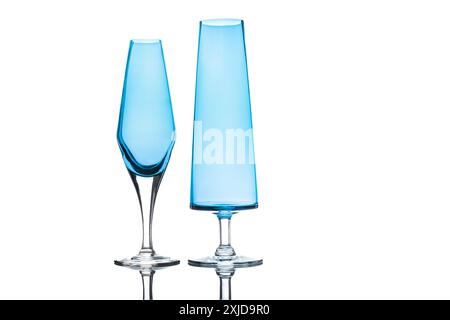 Tall, light blue drinking glasses stand against a clean, white background. The base and part of the stems are reflected in the glossy surface below. Stock Photo