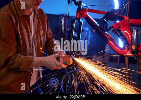 Young handsome man bike mechanic using circular saw for repair work Stock Photo
