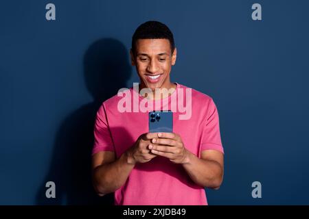 Photo of young funny man using mobile phone chatting with girlfriend happy received sms isolated on dark blue color background Stock Photo
