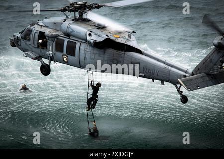 Explosive ordnance disposal technicians from the U.S. Navy, Republic of Korea, Germany, Peru, and Japan return to the aircraft as part of helicopter c Stock Photo