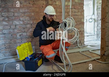 Electrical contractor working with multiple cables during installation precess on construction site. Stock Photo
