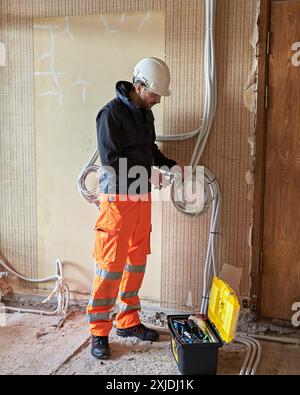 Electrician working with multiple cables during installation precess on construction site. Stock Photo