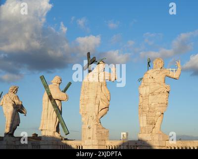 A rear shot of the statues of Jesus Christ and the Apostles on the roof of St. Peter's Basilica on a sunny day in the Vatican City Stock Photo