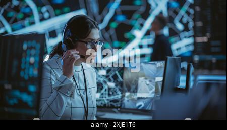 High-Tech Surveillance Office with Specialists Using Satellite Technology with Real-Time Monitoring, CCTV and Traffic Reports. Monitoring Room Technical Support Specialist on a Call with Team Manager Stock Photo