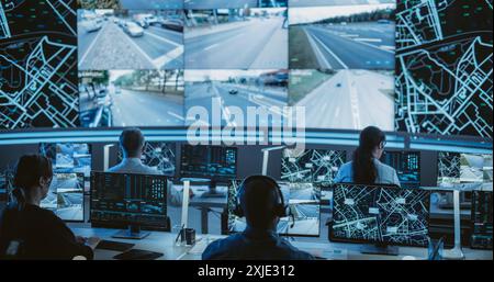 Dark Monitoring Room with Multiethnic Specialists Monitoring Surveillance Feeds and Coordinating Traffic Operations on Desktop Computers. Employees Working in High-Tech Office with Multiple Screens Stock Photo