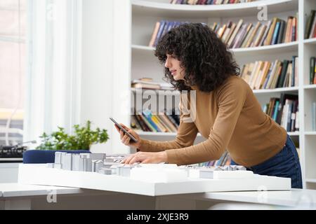 Female architect with city layout using digital tablet at library table with books in background Stock Photo