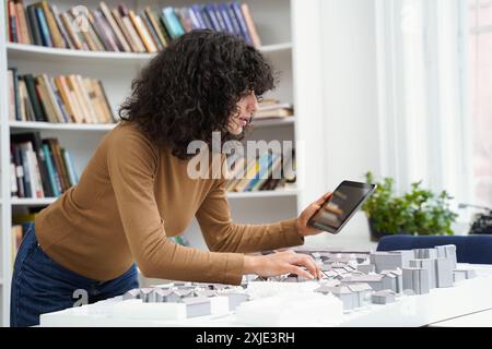 Woman architect using tablet at library table while creating city workout Stock Photo
