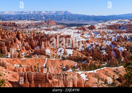 Breathtaking panoramic view of Bryce Canyon's Amphitheater from the Queens Garden Trail. Vibrant red rock hoodoo formations contrast with snow. Stock Photo