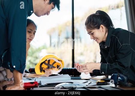 Group of Engineers Collaborating on a Project in a Modern Office Environment with Safety Gear and Blueprints Stock Photo
