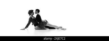 Ballet duo practicing close embrace on floor shows balance, and elegance of their partnership against white studio background. Sepia filter. Stock Photo