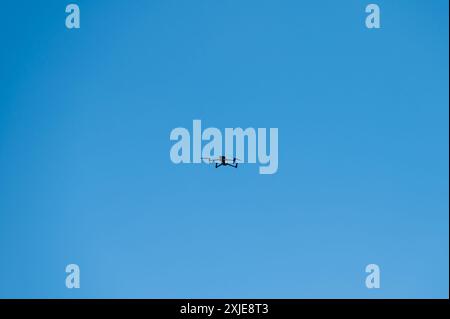 Drone flying in the air at a distance isolated against clear a blue sky. Copy space Stock Photo