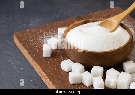 Heap of white granulated sugar in spoon and bowl with sugar cube Stock Photo