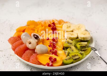 A large plate with sliced various tropical fruits on a light background Stock Photo