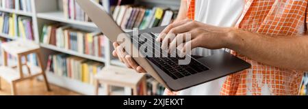 Young man using laptop in library. Stock Photo
