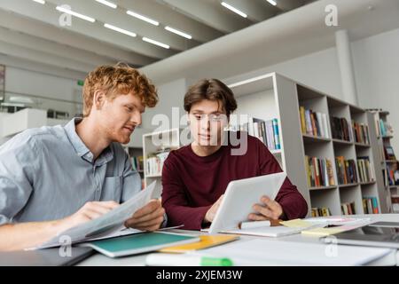 Two young men engage in studying together using a tablet. Stock Photo