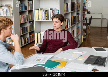 Two young male students concentrated on their books at a library table. Stock Photo