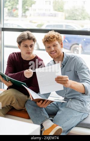 Two men engage in focused study on a windowsill. Stock Photo