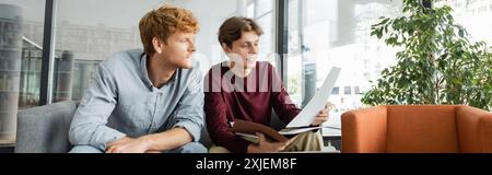 Two male students reviewing papers together on a couch. Stock Photo