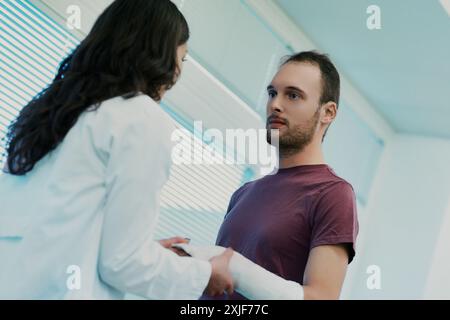 Female doctor carefully wrapping a bandage on a young male patient's arm in a medical office, providing support and care during diagnosis and treatmen Stock Photo