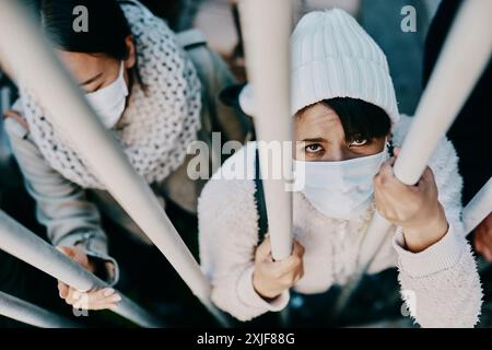 Portrait, mask and woman behind bars in jail for security, travel or immigration in Mexico. Face, border crisis and prison for crime or arrest of Stock Photo