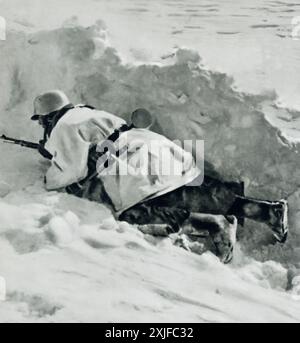 A photograph shows a German soldier crawling next to a snowbank, making his way to the frontline firing position. Taken during Operation Barbarossa in 1941, this image highlights the extreme winter conditions and the challenges faced by German forces as they advanced against Soviet troops on the Eastern Front during the Second World War. Stock Photo