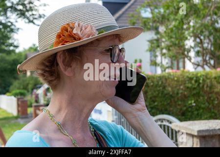 Elderly woman talking on her smartphone, Wustrow, Fischland, Mecklenburg-West Pomerania, Germany Stock Photo