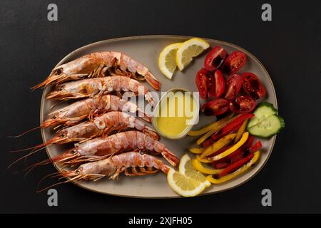 Grilled shrimps with lemon, paprika and sauce on dark background. Stock Photo