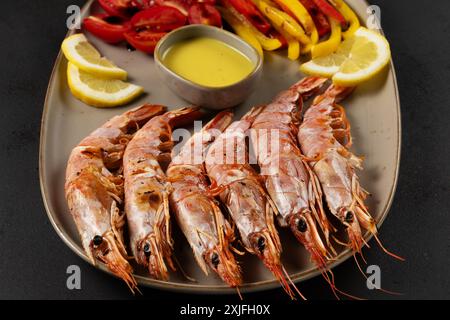 Grilled shrimps with lemon, paprika and sauce on dark background. Stock Photo