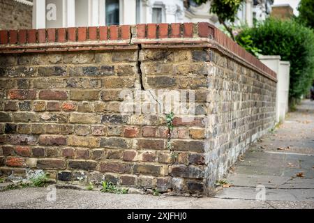 A cracked brick wall in residential suburban British street Stock Photo