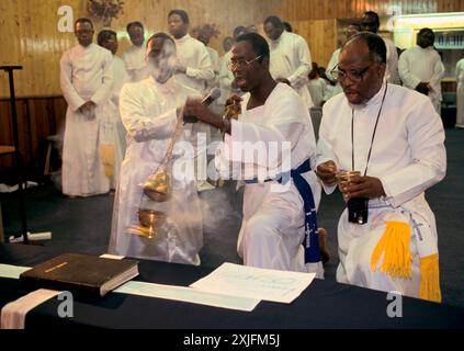 Celestial Church of Christ, the opening of the Seventh Year Parish church. A bible lies on a coffin of a recently departed member of the church community. His son speaks about his father, a microphone is held so the church congregation can hear whats he is saying. The church is mainly attended by Yoruba people from western. Ilford, East London, England 1992. 1990s UK HOMER SYKES Stock Photo