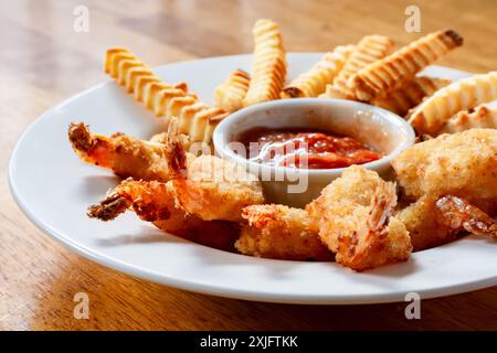 Deep fried shrimp and french fries cooked in an air fryer.  Arranged in shallow white bowl with cocktail sauce in center. Stock Photo