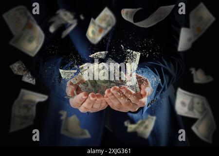 Businessman holding dissolving dollar banknotes in darkness, closeup. Money falling around. Financial crisis Stock Photo