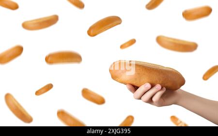Woman holding hot dog bun against flying ones on white background Stock Photo