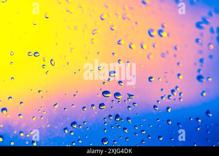 Window with raindrops on it. The raindrops are scattered all over the window, creating a blurry and hazy effect. Scene is calm and peaceful, as the ra Stock Photo