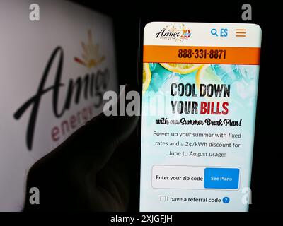 Person holding cellphone with webpage of US company Fulcrum Retail Energy LLC (Amigo Energy) in front of logo. Focus on center of phone display. Stock Photo