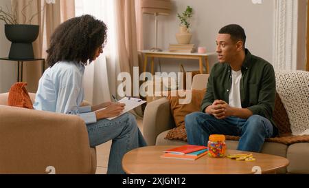 African American woman man consultation doctor appointment psychologist mental health write clipboard notes conversation healthcare patient talk visit Stock Photo