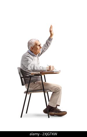 Elderly man sitting in a school chair and raising hand isolated on white background Stock Photo