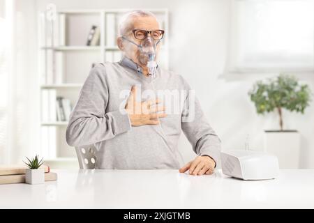 Elderly man with breathing problem using a nebulizer with vapor at home Stock Photo