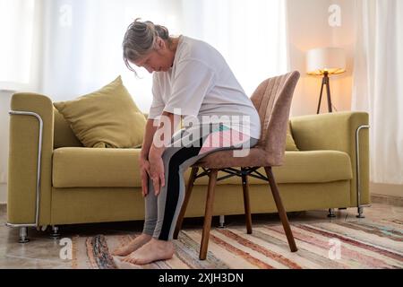 Senior caucasian woman doing doing yoga at home on sofa Stock Photo