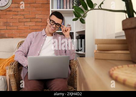 Male author using laptop in armchair at home Stock Photo